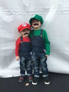 two young boys with fake mustaches and overalls standing in front of a white backdrop