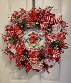 a red and white wreath with an apple on the front door is decorated with ribbon