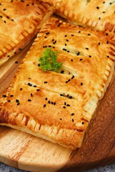 a wooden cutting board topped with four pieces of pie covered in cheese and black sesame seeds