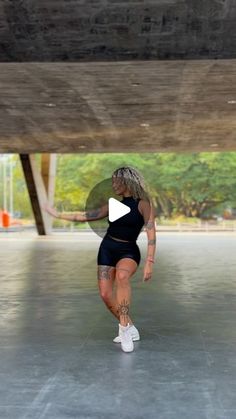 a woman in black shirt and shorts running under a bridge