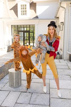 a woman standing next to two children dressed up in costumes and holding onto stuffed animals