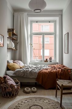 a bedroom with a bed, window and rug on the floor in front of it