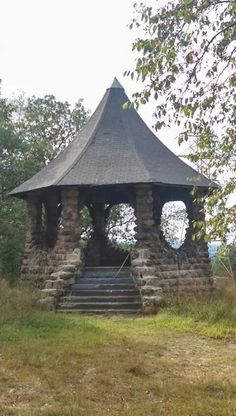 an old stone gazebo sitting in the middle of a field