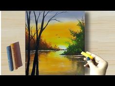 someone is painting a sunset scene with yellow and orange colors on the water, while holding a marker in their left hand