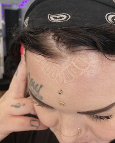 a woman with tattoos on her face and head is holding her hand to her ear