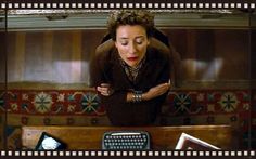 a woman sitting at a desk in front of a typewriter with her hands on the keyboard