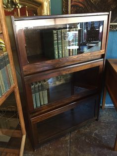 a wooden book shelf with many books on it and a mirror in the corner behind it