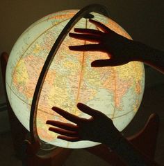 two hands reaching out towards a glowing globe