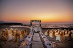 an outdoor wedding setup on the beach at sunset