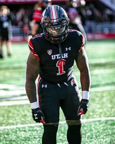 a football player is standing on the field with his hands in his pockets while wearing black and red uniform