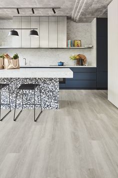 a kitchen with blue cabinets and white countertops, two bar stools in front of the island