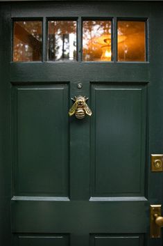 a green front door with a metal bee on it's side and glass windows