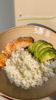 a plate with rice, avocado and salmon on it next to a slice of cucumber