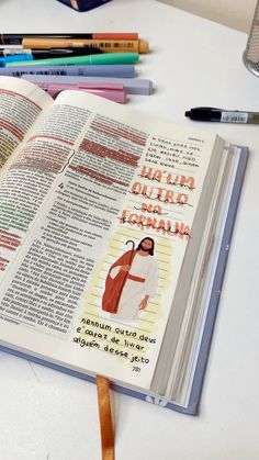 an open bible on a table with crayons and pencils next to it