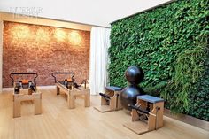 a living room filled with furniture next to a wall covered in green plants and wooden benches