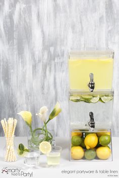 two clear containers filled with lemons and limes next to a glass of water