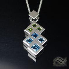 "A simple modern design depicting two overlapping triangles in peridot and topaz. A made in solid sterling silver. I wanted a sleek and modern design with minimal distractions form the design and shapes. I created a back set setting for the stones to give them the appearance of flush set stones, which would be near impossible to do normally with stones of this size and shape. Features: ~5mm Natural Peridot stones, all square cuts ~6mm Natural Swiss Blue Topaz, all square cuts ~8mm Natural Swiss Modern Silver Jewelry With Birthstone, Modern Peridot Jewelry For Formal Occasions, Modern Green Birthstone Jewelry, Modern Sterling Silver Jewelry With Gemstones, Modern Green Peridot Jewelry, Modern Silver Jewelry With Tension Setting, Modern Green Multi-stone Jewelry, Modern Geometric Jewelry For Anniversary, Modern White Gold Multi-stone Jewelry