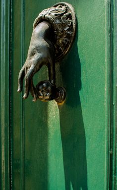 a door handle on a green door with a dog's head hanging from it