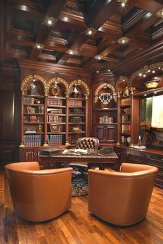 a room with two chairs, a desk and bookshelves on the wall in front of it