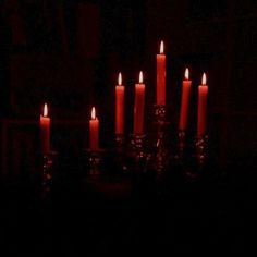 many lit candles in the dark on a table