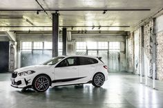 a white car is parked in an empty garage with brick walls and exposed concrete flooring