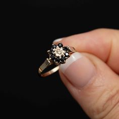 a woman's hand holding a ring with black and white flowers