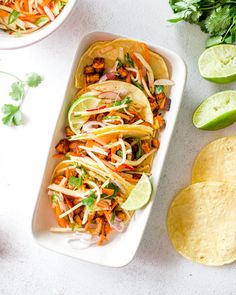 two tacos with shredded carrots and cilantro on the side