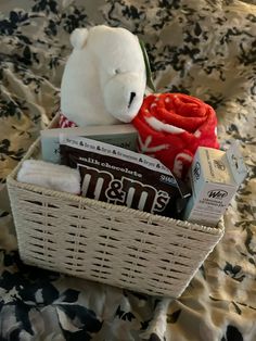 a teddy bear sitting on top of a bed next to a basket filled with food