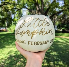 someone holding up a white pumpkin with the words little pumpkin coming february 20th on it