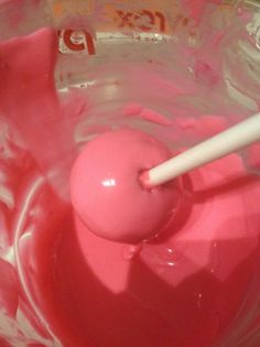 a pink substance in a bowl with a toothbrush sticking out of the top,