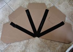 three pieces of cardboard sitting on top of a tile floor next to a pair of scissors