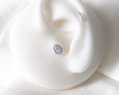 an image of a pair of earrings on top of a white object that is laying down