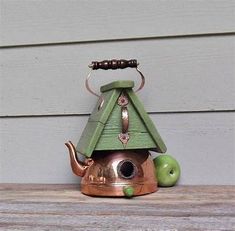 a tea kettle with a green roof and an apple