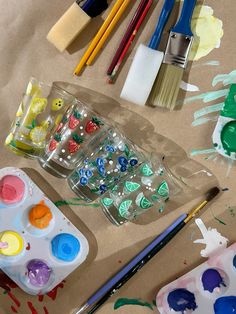 some paint brushes and paints sitting on top of a brown paper covered with watercolors