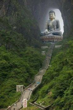 a large buddha statue sitting on top of a lush green hillside next to a tunnel