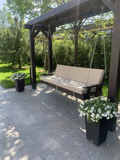 an outdoor swing with two planters on the ground