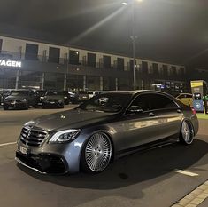 a silver car parked in front of a building at night with lights shining on it