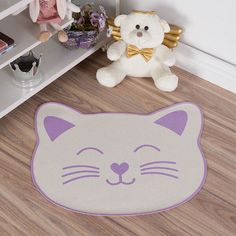 a white and purple cat rug with a teddy bear next to it on the floor