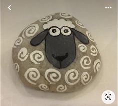 a rock with a sheep painted on it's face and swirls around the eyes