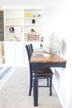 a desk with a globe on top of it in front of a bookshelf