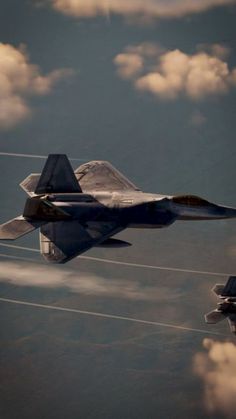 two fighter jets flying in the sky above clouds