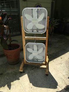 two white fans sitting on top of a wooden stand next to a potted plant