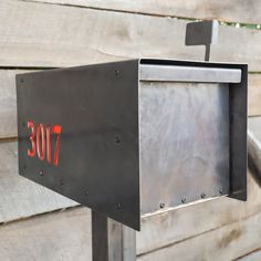 a mailbox with the number seventy on it is next to a wooden wall and metal railing