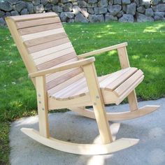 a wooden rocking chair sitting on top of a cement slab in front of a stone wall