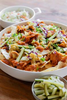 a white bowl filled with nachos covered in cheese and sauce next to another bowl full of green beans