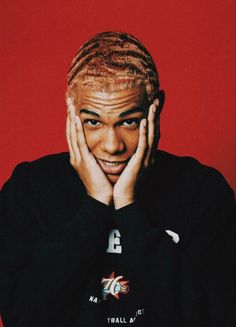 a man with his hands on his face and wearing a black shirt against a red background