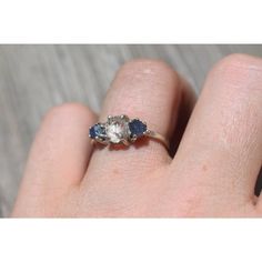 a woman's hand holding a ring with three stone stones on the middle of it