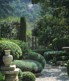 a stone path in the middle of a garden with trees and bushes on either side