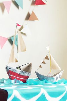 two paper boats sitting on top of a blue and white tablecloth covered table cloth