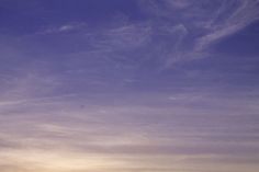 two people standing on the beach with their surfboards under a purple sky at sunset